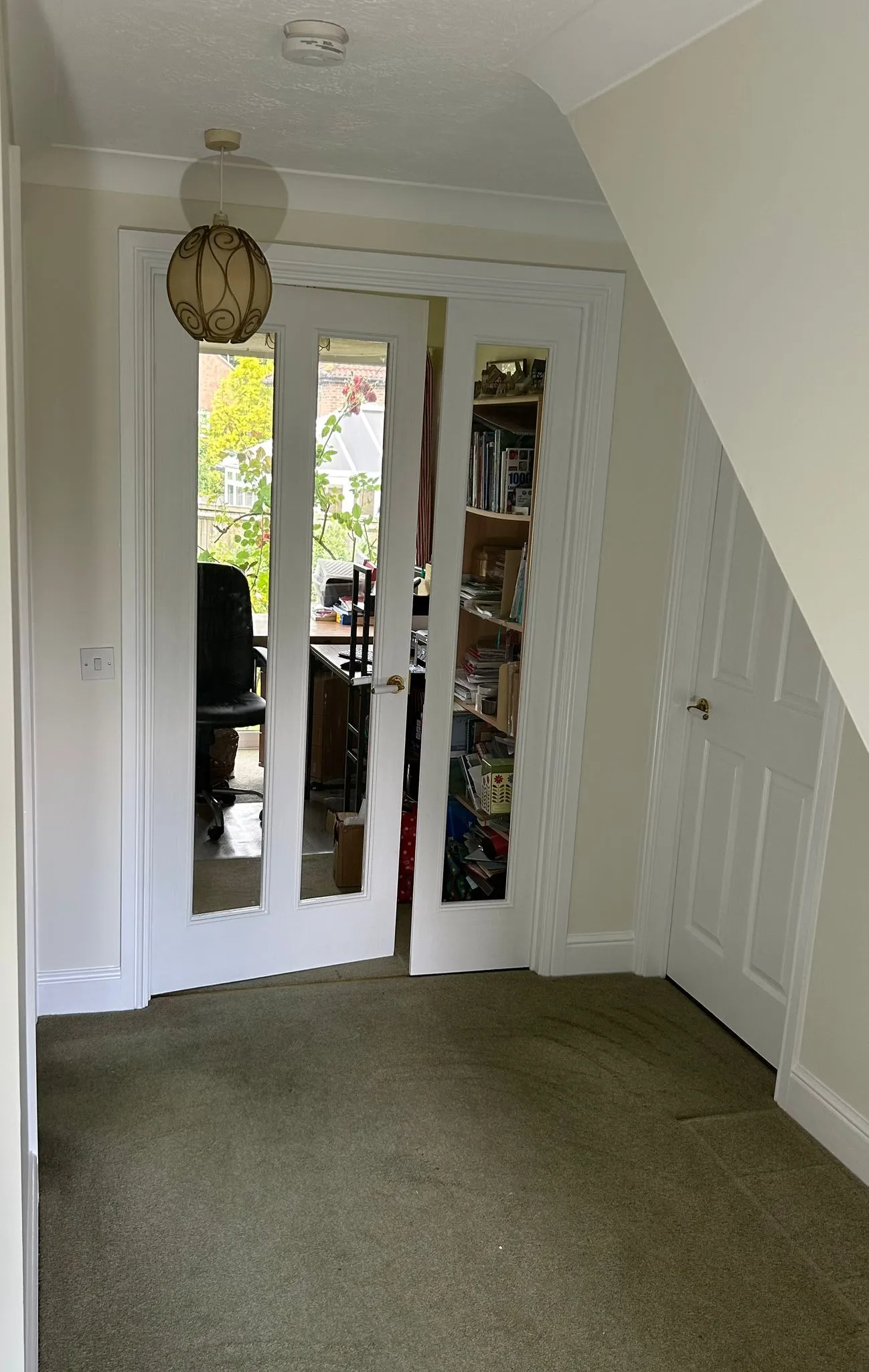 a room with two doors and a book shelf