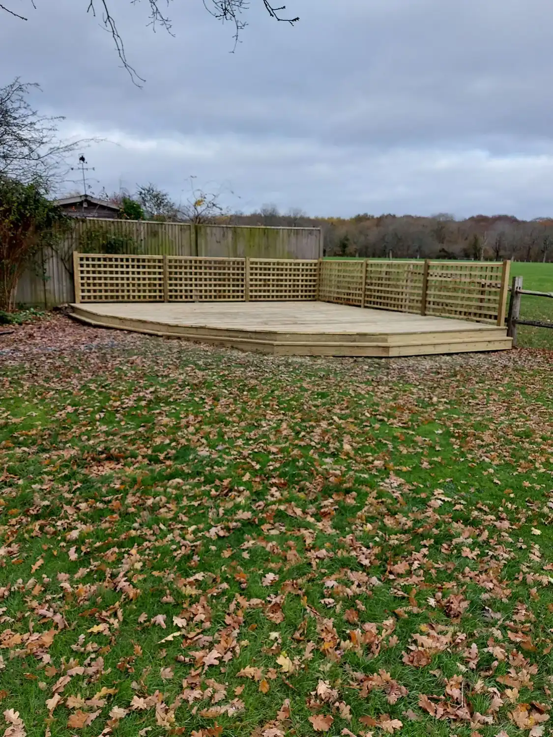 A wooden deck in the middle of a grassy area.