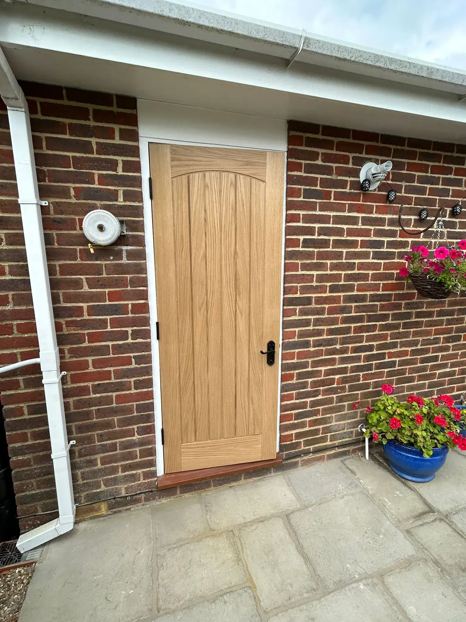 A brick house with a wooden door and flower pots.